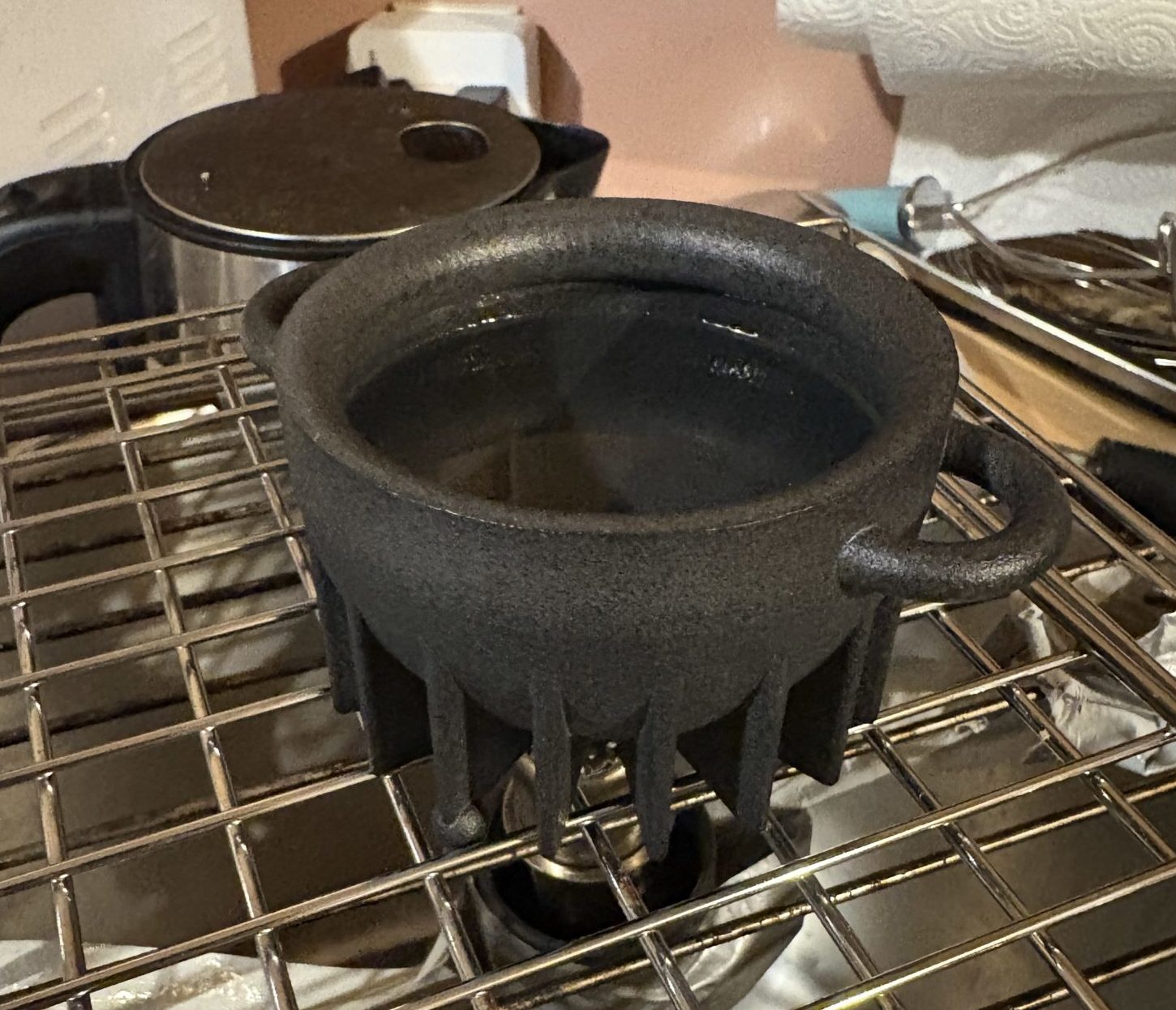 The EcoPot pot with water inside, over a metal grate.