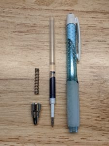 The three parts of a pen laid out orderly on a table.